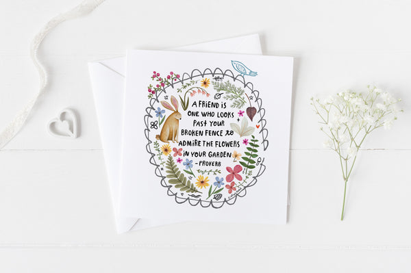 5x5 greeting card by Eliza Todd featuring a garden fence, a rabbit and beautiful flowers, saying "A friend is one who looks past your broken fence to admire the flowers in your garden." - APeaceofWerk.com