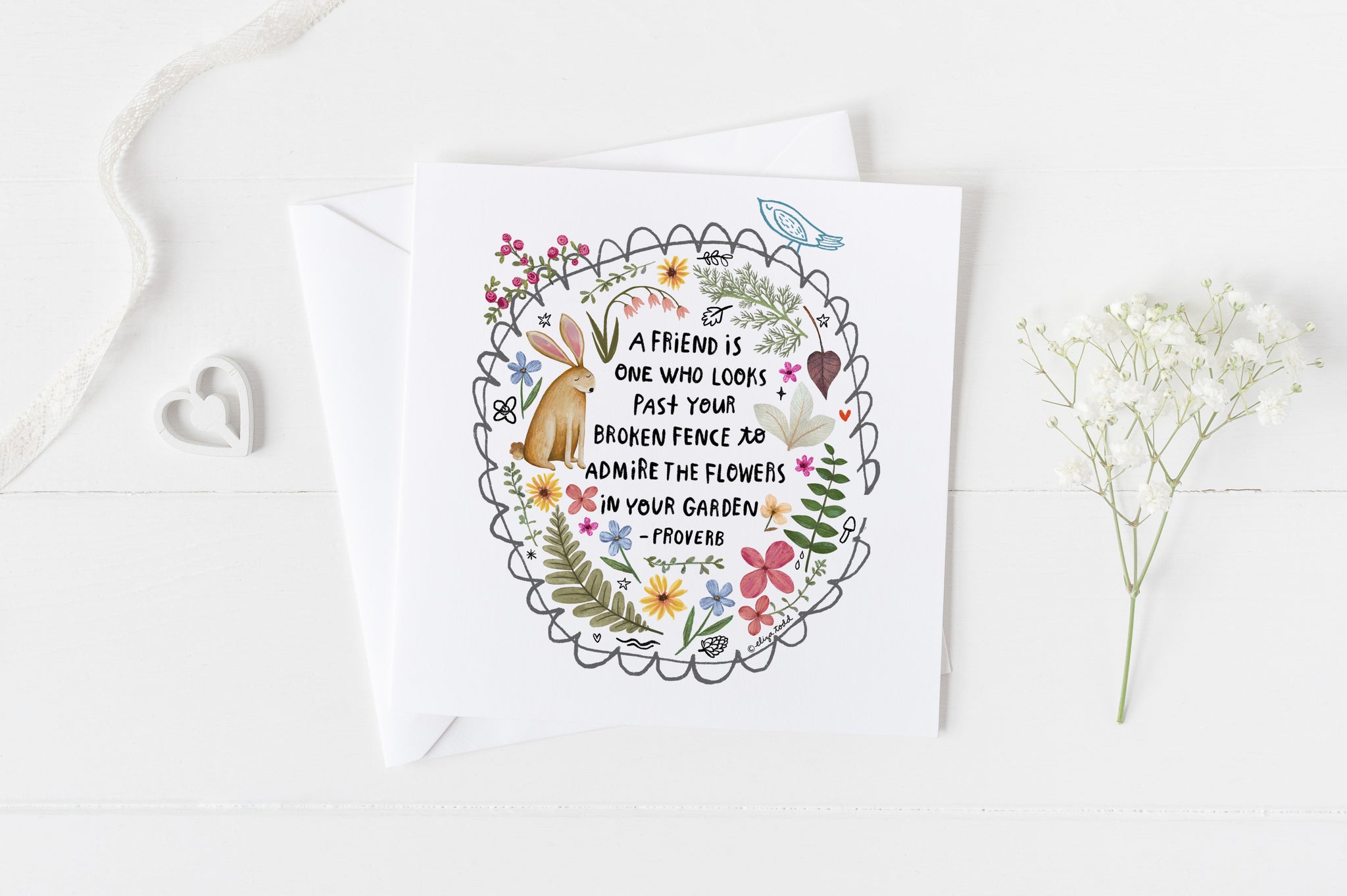 5x5 greeting card by Eliza Todd featuring a garden fence, a rabbit and beautiful flowers, saying "A friend is one who looks past your broken fence to admire the flowers in your garden." - APeaceofWerk.com